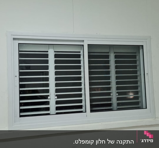 תריסים לבנים על חלון זכוכית במסגרת לבנה